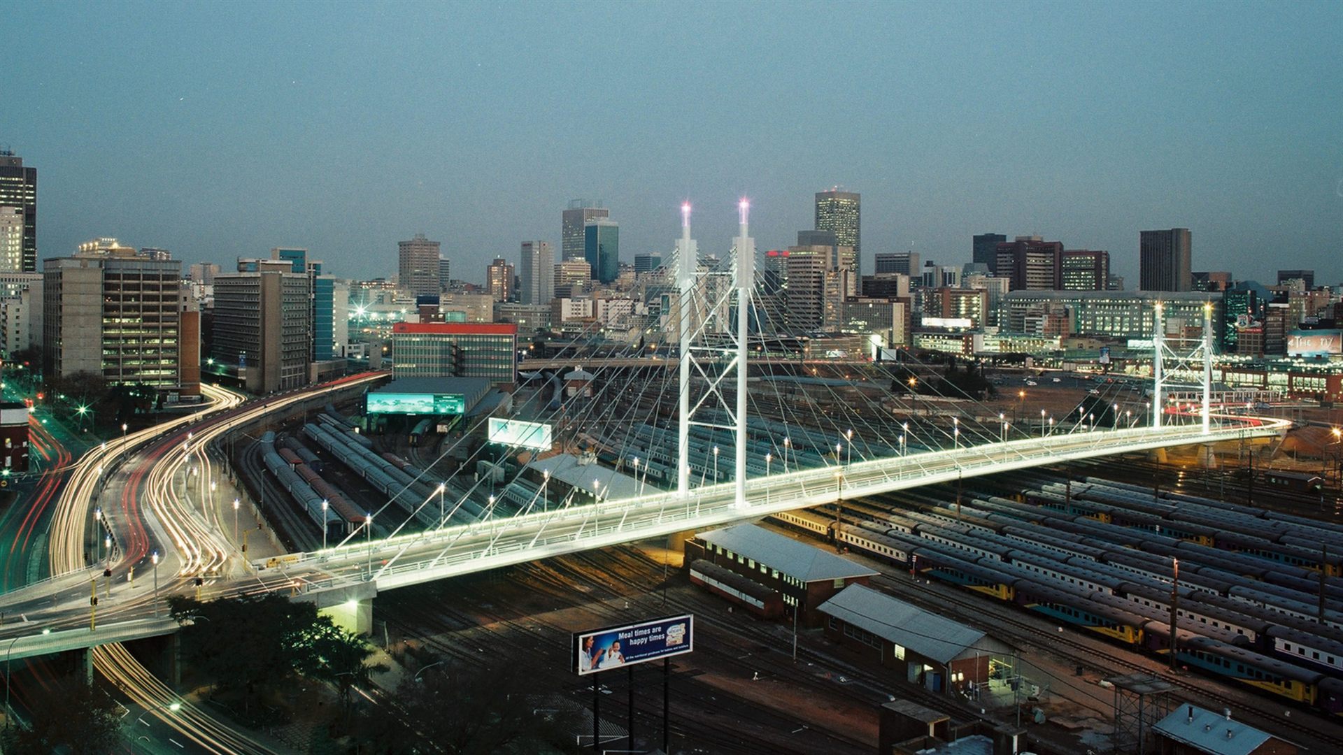 The Nelson Mandela Bridge lit at dusk over the Johannesburg city skyline